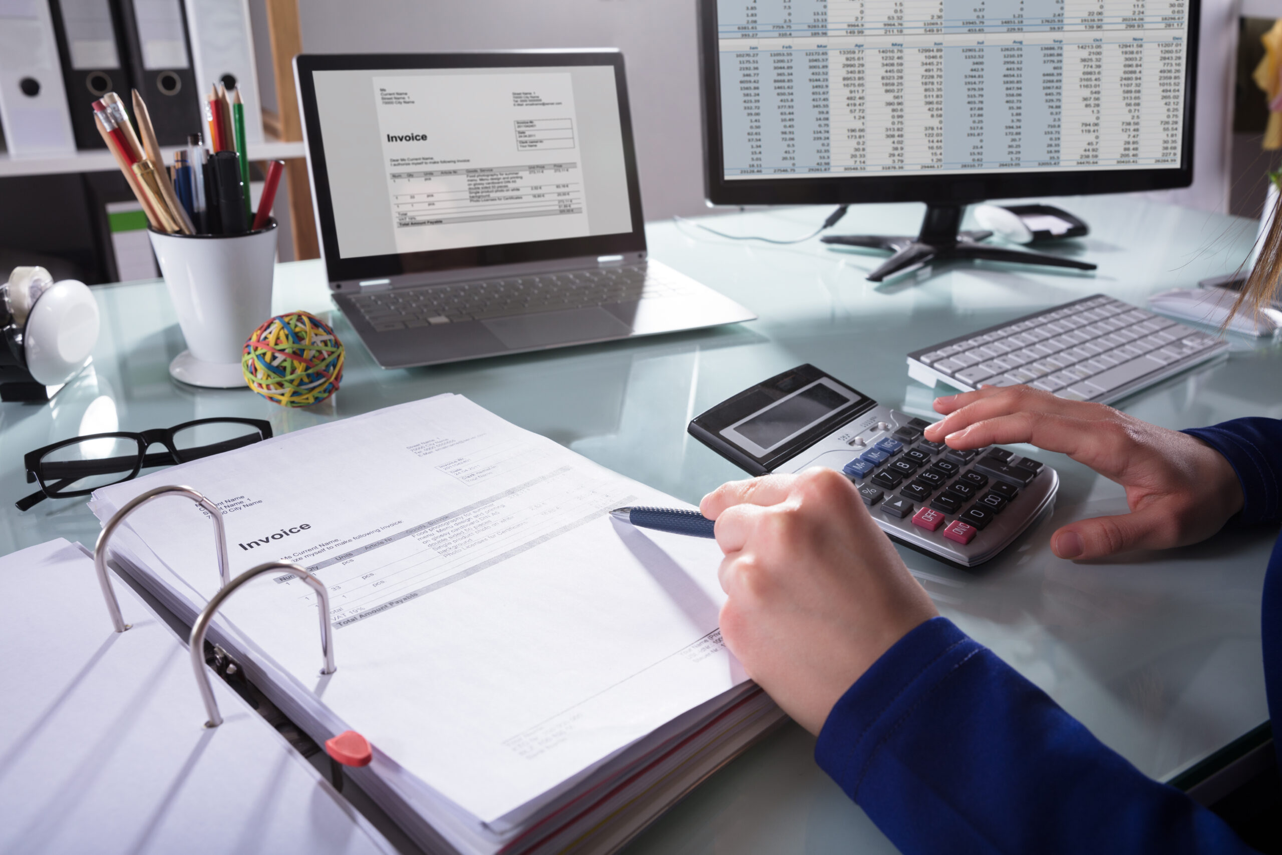 Close-up,Of,A,Businessperson's,Hand,Calculating,Invoice,At,Workplace